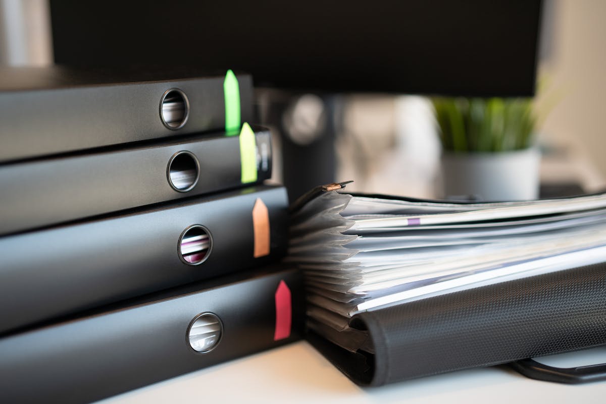 Ring binders full of documents stacked on a desk.