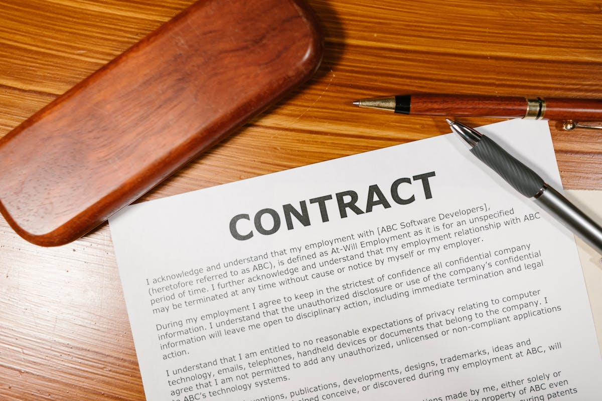 A warranty document open on a wooden desk with a pen across it.